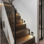 Multiple recessed motion sensor stair lights installed along indoor staircase wall showing evenly spaced LED night lights illuminating each step